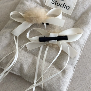 Detail of ballet style hair clips with cream satin bows, fur balls and long ribbons