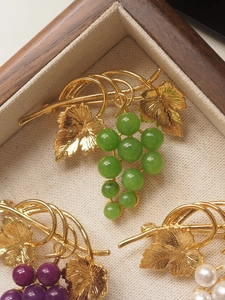 Macro shot of grape-shaped brooches with colorful beads in a wooden jewelry gift box