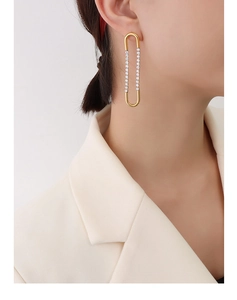 Close-up of gold U-shaped earrings with zircon inlay worn by a model in a beige suit