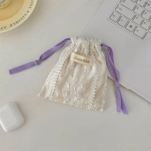 Detailed view of cream velvet drawstring bag with lace edges and purple braided cord