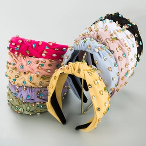 Macro view of velvet knotted headbands featuring colorful rhinestones and faux pearls