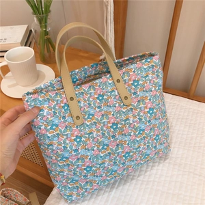 Detail of floral tote bag with reinforced leather handles and rivet stitching