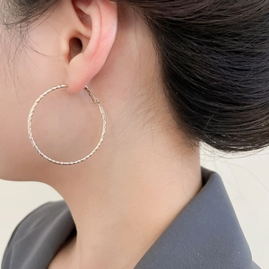 Detailaufnahme großer goldener Creolen mit Hammerschlag-Optik an einem Model