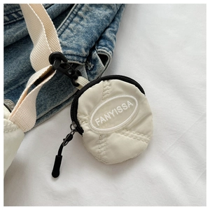 Détail d'un petit porte-monnaie en nylon matelassé blanc cassé sur un sac en jean
