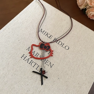 Detailed macro view of a red cat pendant with black bow and small cross charms on a book