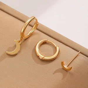 Close-up of gold moon and star earring set on a textured light brown background
