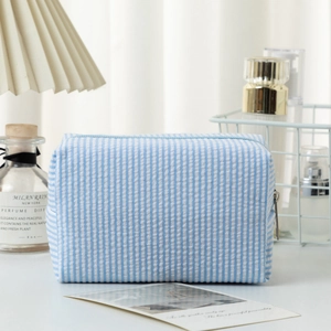 Close-up of blue seersucker striped toiletry bag with metal zipper and fabric texture