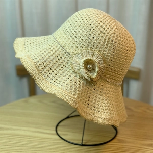 Detail of beige straw sun hat featuring hollow texture and elegant floral decoration