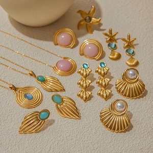 Detailed flat lay of golden ocean-style jewelry with shells and turquoise on beige surface