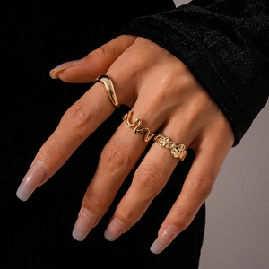 Close-up of three irregular gold rings with wavy and molten textures on a model hand