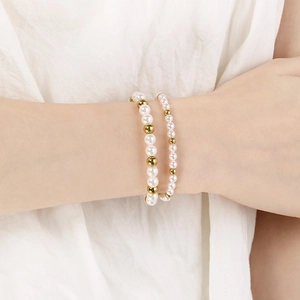 Elegantes Set aus zwei Armbändern mit weißen Perlen und goldenen Edelstahlperlen am Handgelenk