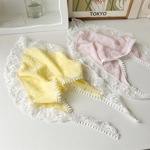 Flat lay of yellow and pink floral lace headscarves with ruffled texture and pom-pom trim