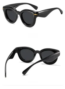 Detail view of black thick round sunglasses featuring gold rivet accents on the temples