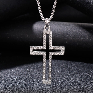 Detailed view of silver cross pendant with sparkling crystals on dark textured fabric
