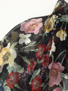 Detail of black chiffon fabric with colorful floral embroidery and pleated texture