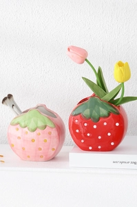 Detailed view of red and pink ceramic strawberry-shaped storage jars side by side