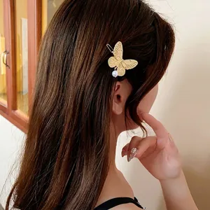 Elegant gold butterfly hair clip with a pearl drop accessory on long brown hair