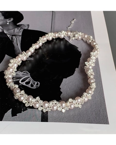 Detailed view of woven pearl necklace with zircon floral accents on a vintage background