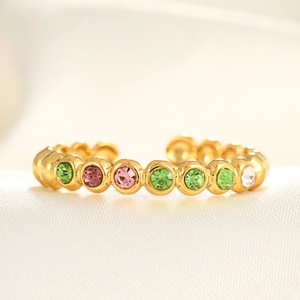 Macro detail of adjustable gold ring featuring multi-colored micro-pave zircons on white silk