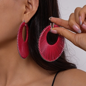 Detail of red woven geometric hoop earring with silver beads on a female model