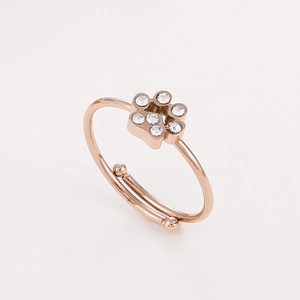 Détail d'une bague patte de chien en or rose avec zircons sur fond blanc pur
