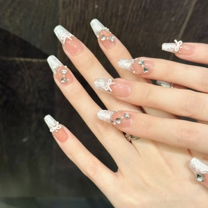 Detailed close-up of handmade press-on nails with 3D bows and silver heart rhinestones