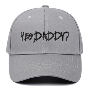 Detail of grey baseball cap featuring black YES DADDY embroidery and cotton texture