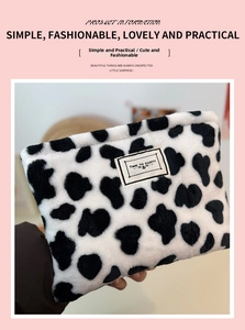 Detail of plush cow print coin purse featuring a black and white pattern and textile label