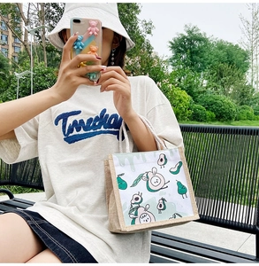 Outdoor shot of a cream canvas tote bag with a cute avocado print and white rope handles