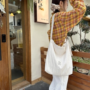 Detail of the pleated cream white canvas tote bag with a minimalist woven label