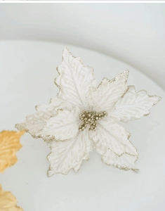 Macro view of a white artificial poinsettia flower with golden glitter edges for Christmas