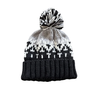 Black and white knit beanie with geometric jacquard pattern and fluffy pom-pom top