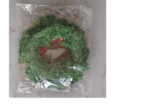 Detailed view of green Christmas wreath with red ribbon bow in protective clear packaging