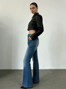 Détail du jean évasé taille haute avec braguette à boutons et délavage du denim