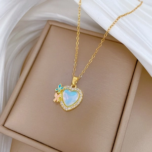 Detail of gold heart pendant with iridescent stone, colorful butterflies and crystals