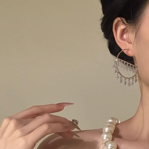 Detail of silver hoop earrings with geometric zircon tassels on a model's profile