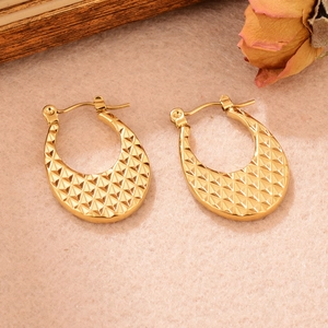 Vue rapprochée des boucles d'oreilles dorées en U avec motif losange sur fond rose