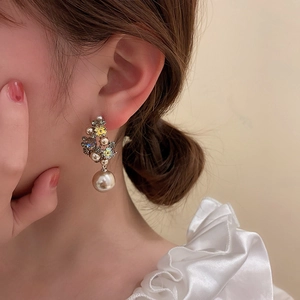 Close-up of elegant flower earring with pearls and colorful rhinestones on a model