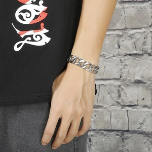 Men's silver stainless steel Cuban link bracelet on model's wrist with streetwear style