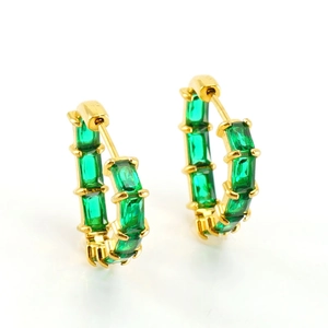 Détail de créoles dorées avec zircons vert émeraude de style vintage chic