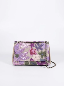 Close-up of intricate colorful floral embroidery and sequins on beige woven texture