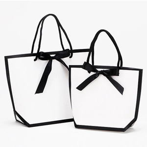 Minimalist white paper gift bags with black borders and elegant ribbon bows in two sizes
