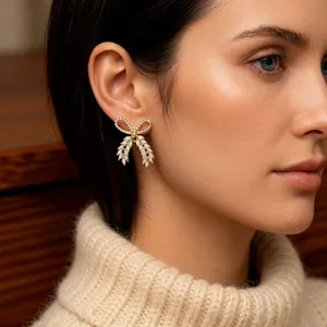 Elegant gold plated bow earrings with white zircon crystals on model wearing beige knit