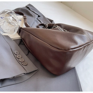 Detail of dark brown leather underarm bag with white contrast stitching and silver chain