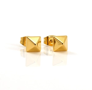 Vue macro de boucles d'oreilles pyramides dorées géométriques au fini poli miroir