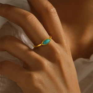 Close-up of a golden marquise-cut turquoise ring worn elegantly on a finger