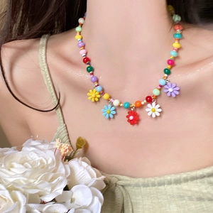 Close-up of handmade colorful beaded necklace with multi-color daisy charms on model