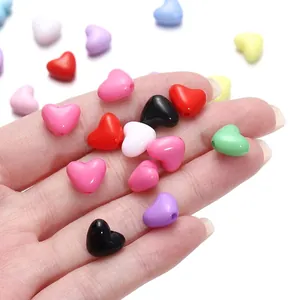 Colorful acrylic heart beads for DIY jewelry making held in hand for size visualization