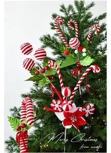 Close-up of red and white candy cane ornaments with holly leaves on a festive Christmas tree