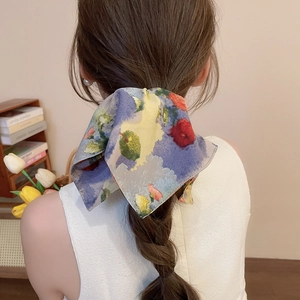 Detail of floral silk scarf hair tie styled in a large bow on a low ponytail